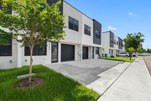 A modern residential building with a tree in the front yard, a clear sky, and parked cars. - Close to DT Tampa Newly Designed Town Home (Tampa)