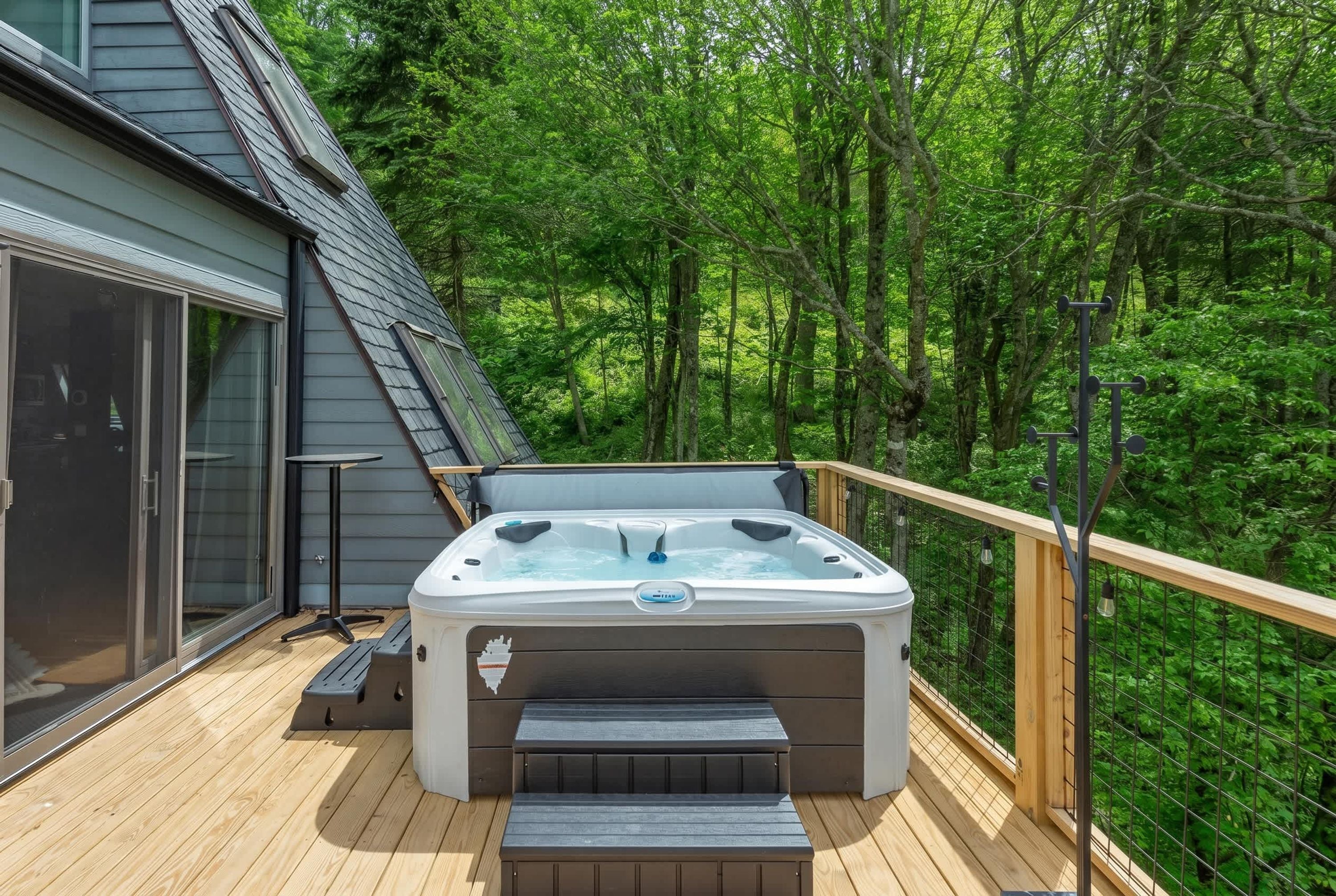 Un jacuzzi en una terraza de madera rodeado por un bosque.