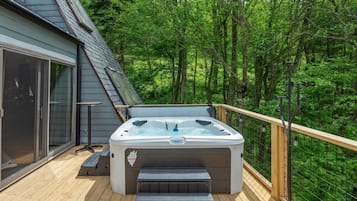 A hot tub on a wooden deck surrounded by a forest.