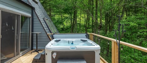 Un jacuzzi en una terraza de madera rodeado por un bosque.
