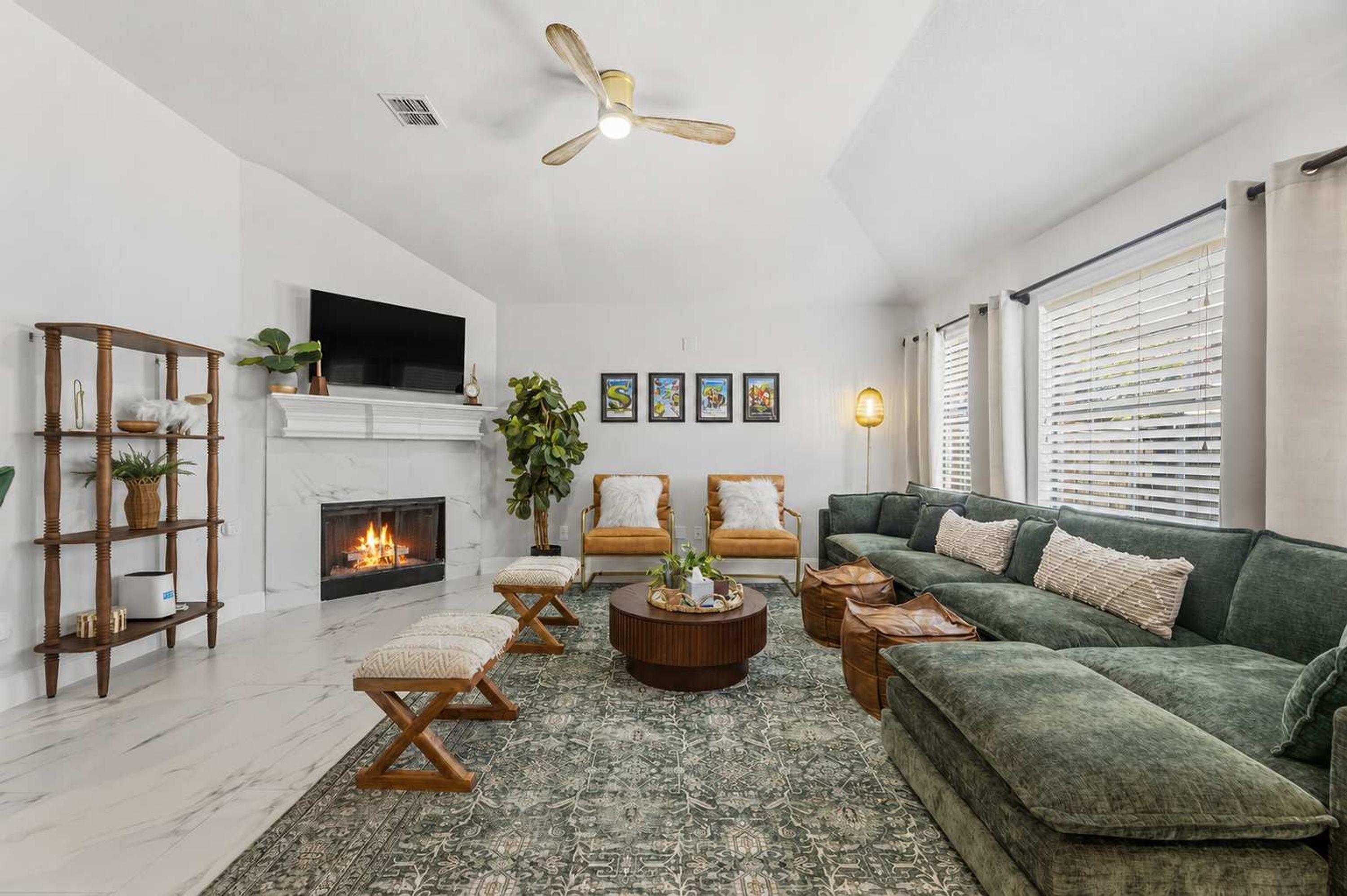 A modern living room with a fireplace, a green sofa, a coffee table, and a ceiling fan.
