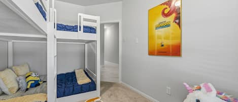 Ett barnrum med våningssängar, en mjukdjursleksak föreställande en Minion, en mjukdjursleksak föreställande en enhörning och en filmplakat på väggen.