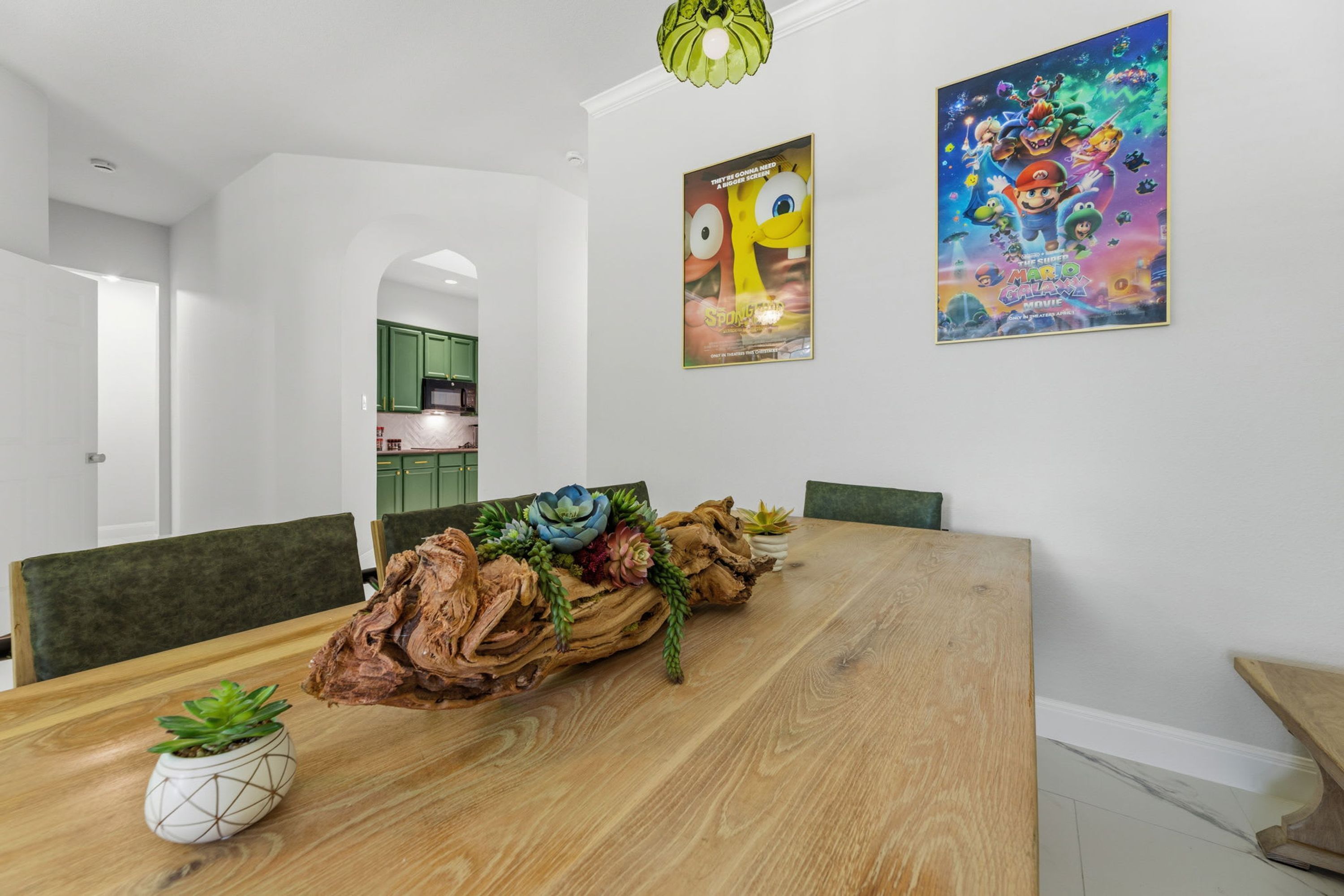 Uma sala de jantar com uma mesa de madeira, cadeiras, um centro de mesa e dois quadros na parede.