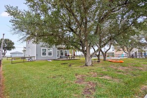 A grassy yard with a house, a tree, and a kayak. - Copano Ridge Private Pool Priv Dock Pet Friendly (Rockport)