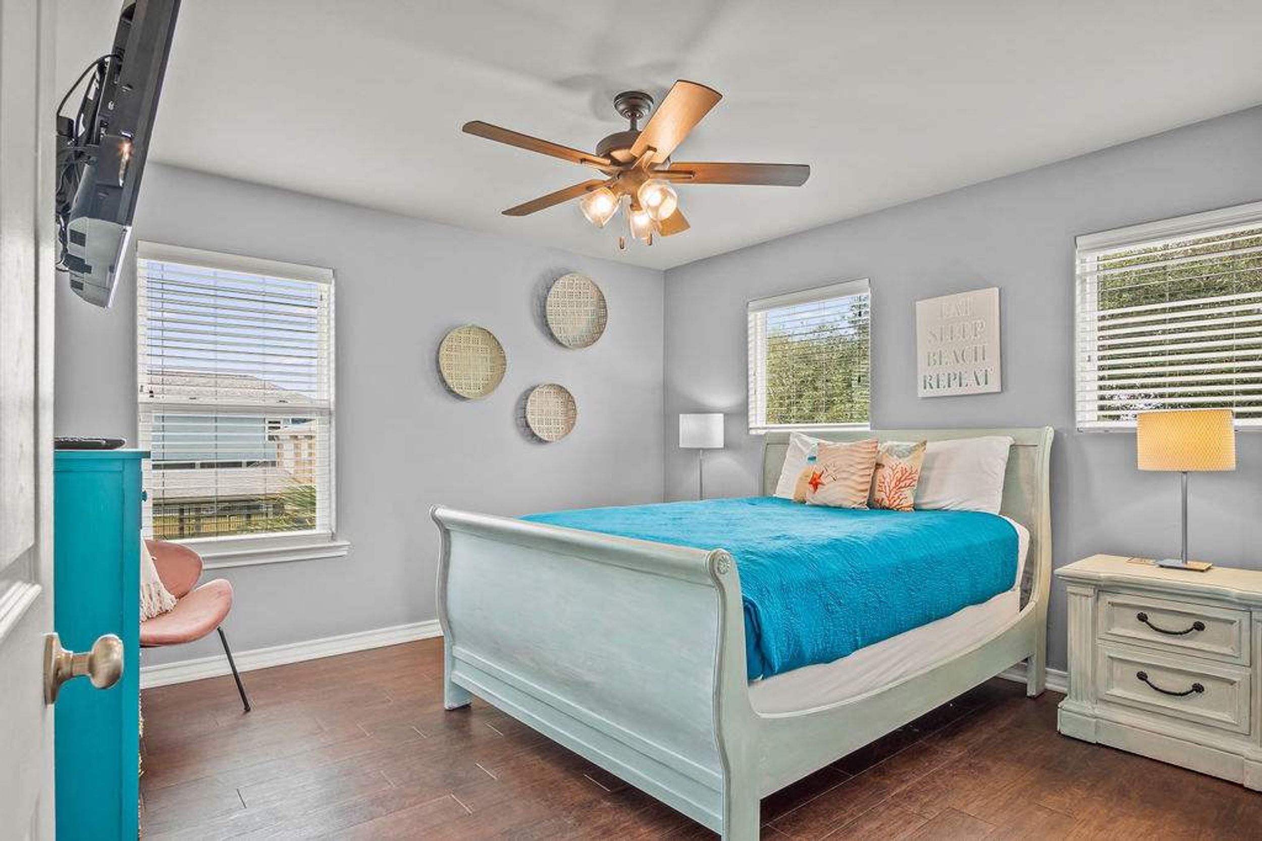 A bedroom with a bed, a nightstand, a chair, a ceiling fan, and a window with blinds.
