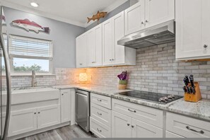 A kitchen with white cabinets, a stainless steel refrigerator, and a backsplash. - Copano Ridge Private Pool Priv Dock Pet Friendly (Rockport)