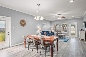 A dining area with a wooden table and chairs, a ceiling fan, and a chandelier. - Copano Ridge Private Pool Priv Dock Pet Friendly (Rockport)