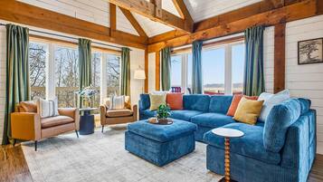 A spacious living room with a large blue sectional sofa, a coffee table, and a fireplace.