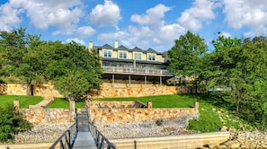A multi-story house with a stone retaining wall, a wooden deck, and a staircase leading to the entrance. - Luxury Lake Escape Dock Basketball Views (Chico)