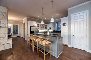 A spacious kitchen with a central island, bar stools, pendant lighting, and a large window. - Luxury Lake Escape Dock Basketball Views (Chico)