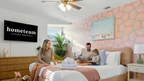 Una familia en un dormitorio moderno con una cama, un televisor y una pared con un diseño.
