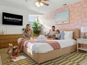 Eine Familie in einem modernen Schlafzimmer mit Bett, Fernseher und einer Wand mit Muster.