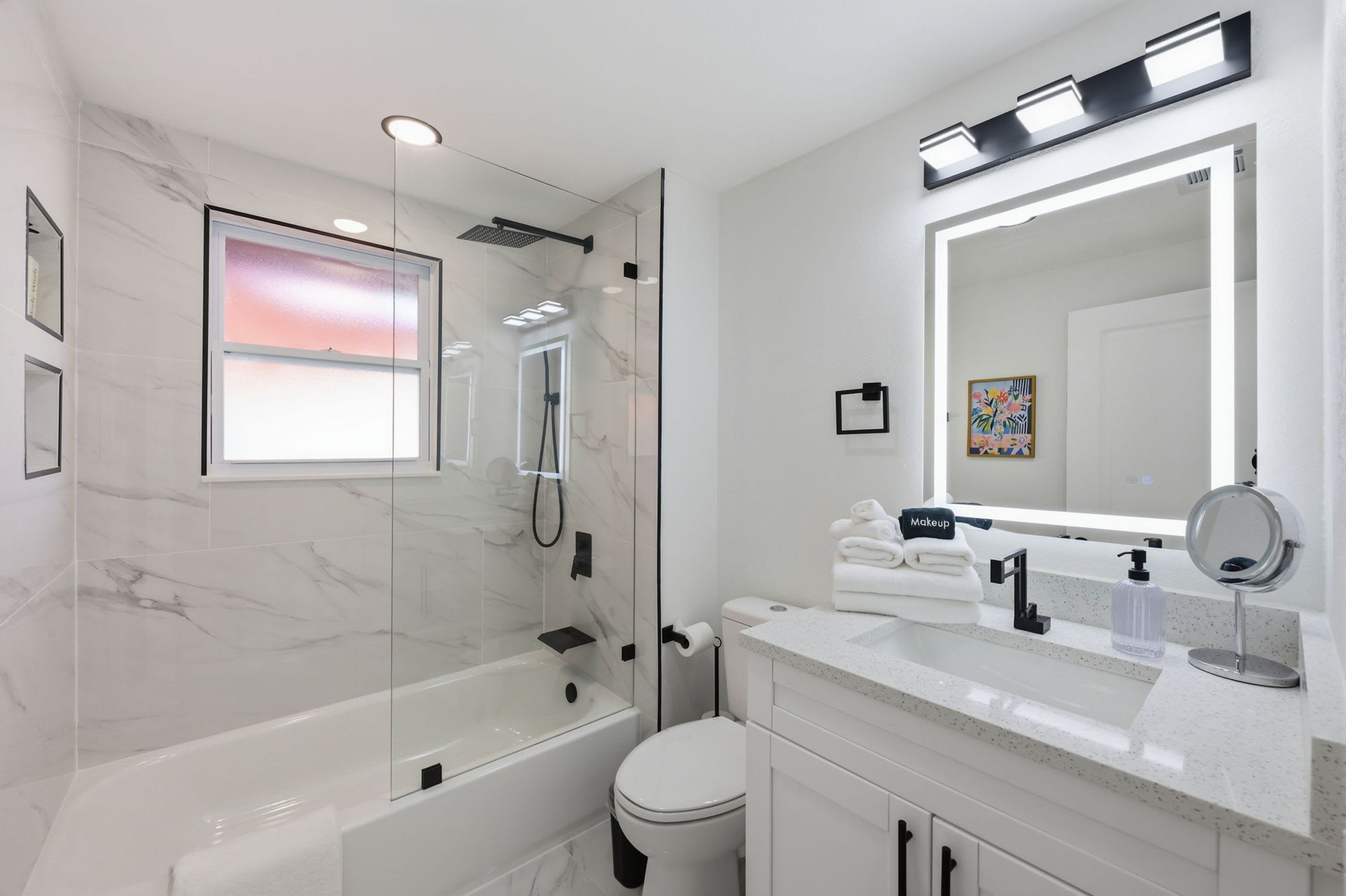 A modern bathroom with a glass-enclosed shower, a white toilet, and a vanity with a mirror.