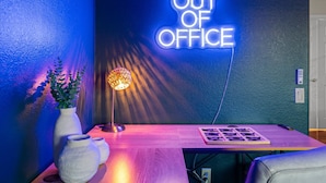 A room with a neon sign reading 'OUT OF OFFICE' on the wall, a table with a lamp, and a plant. - Epic Family Getaway Sport Court Heated Pool (Scottsdale)