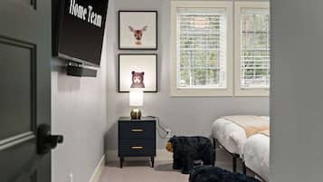 A bedroom with a bed, a nightstand with a lamp, a wall-mounted TV, and two framed animal pictures.