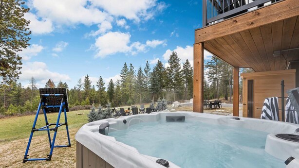 Un jacuzzi en una terraza de madera con vista a un bosque.