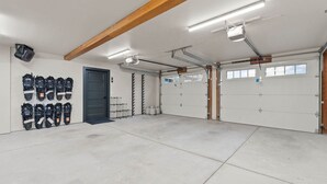 Un garaje con dos puertas, iluminación en el techo y un estante con objetos en la pared.
