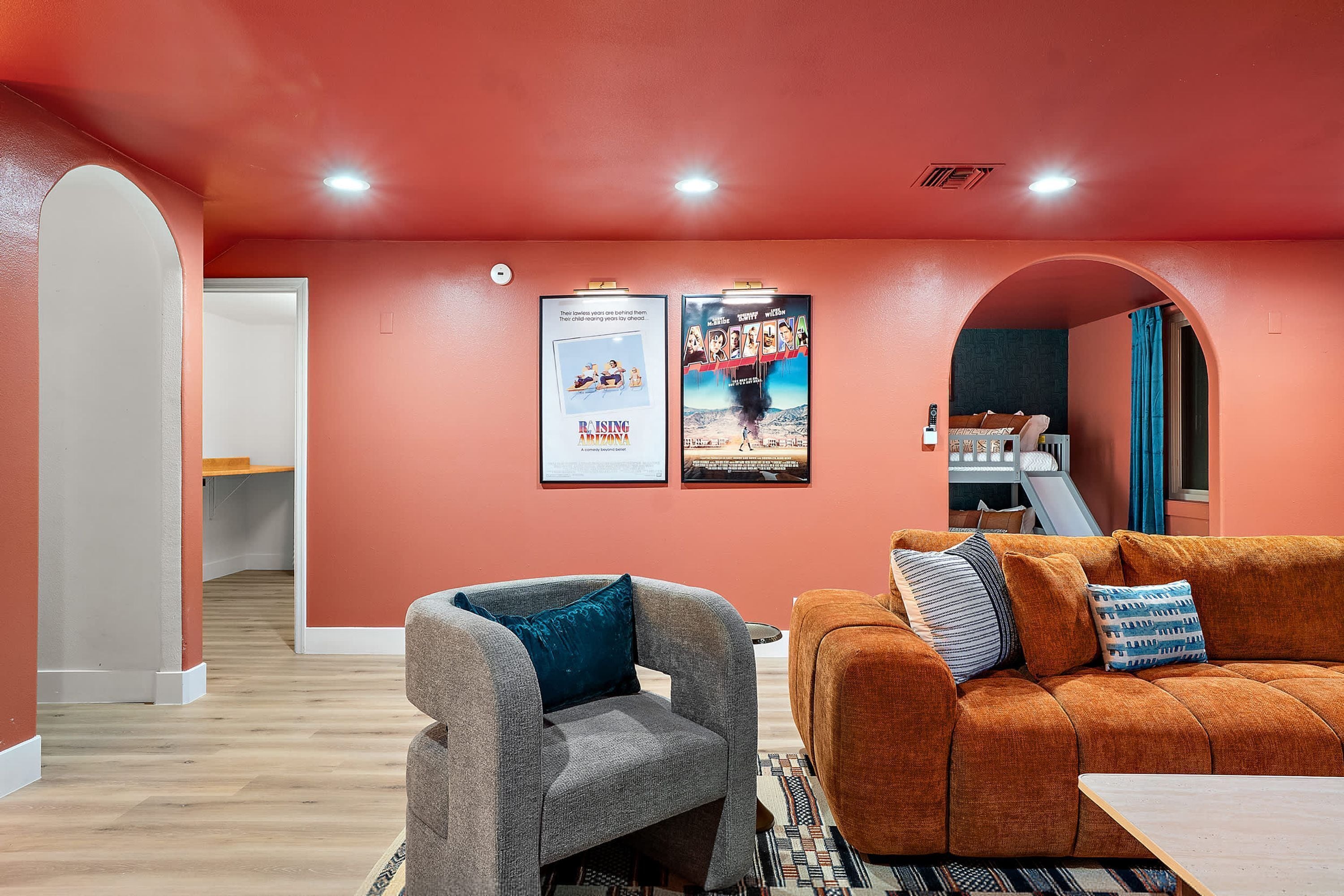 Una sala de estar con sofá, sillón y un cartel en la pared.