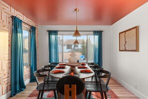 A dining area with a round table, chairs, and a pendant light. - AZ Game House Sport Court - Golf - Pool - Games (Peoria)