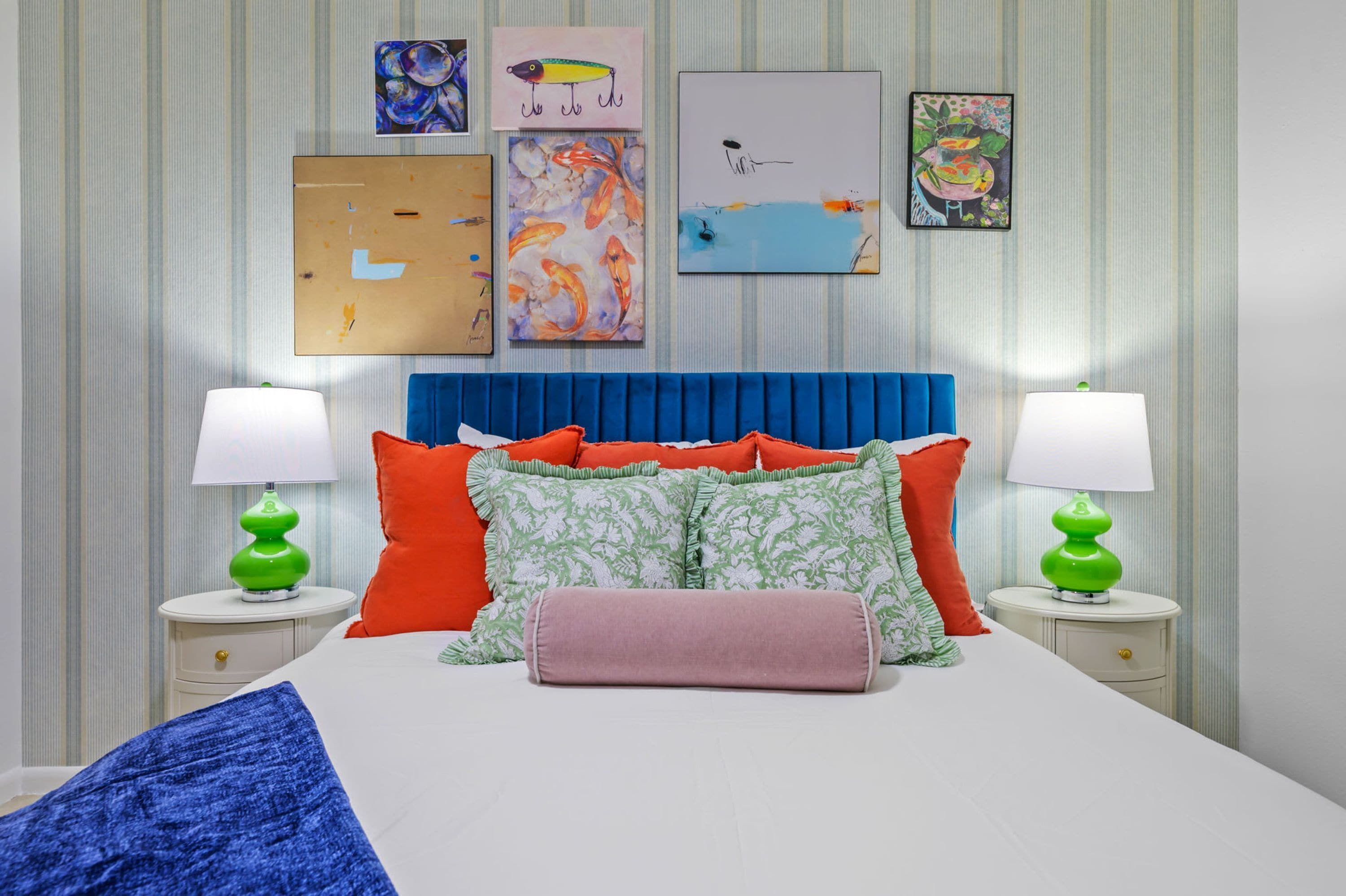 A bedroom with a bed, pillows, two bedside tables, and wall art.