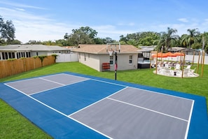 Ein Wohnhaus mit Tennisplatz, Schwimmbad und Sitzgelegenheit im Freien.