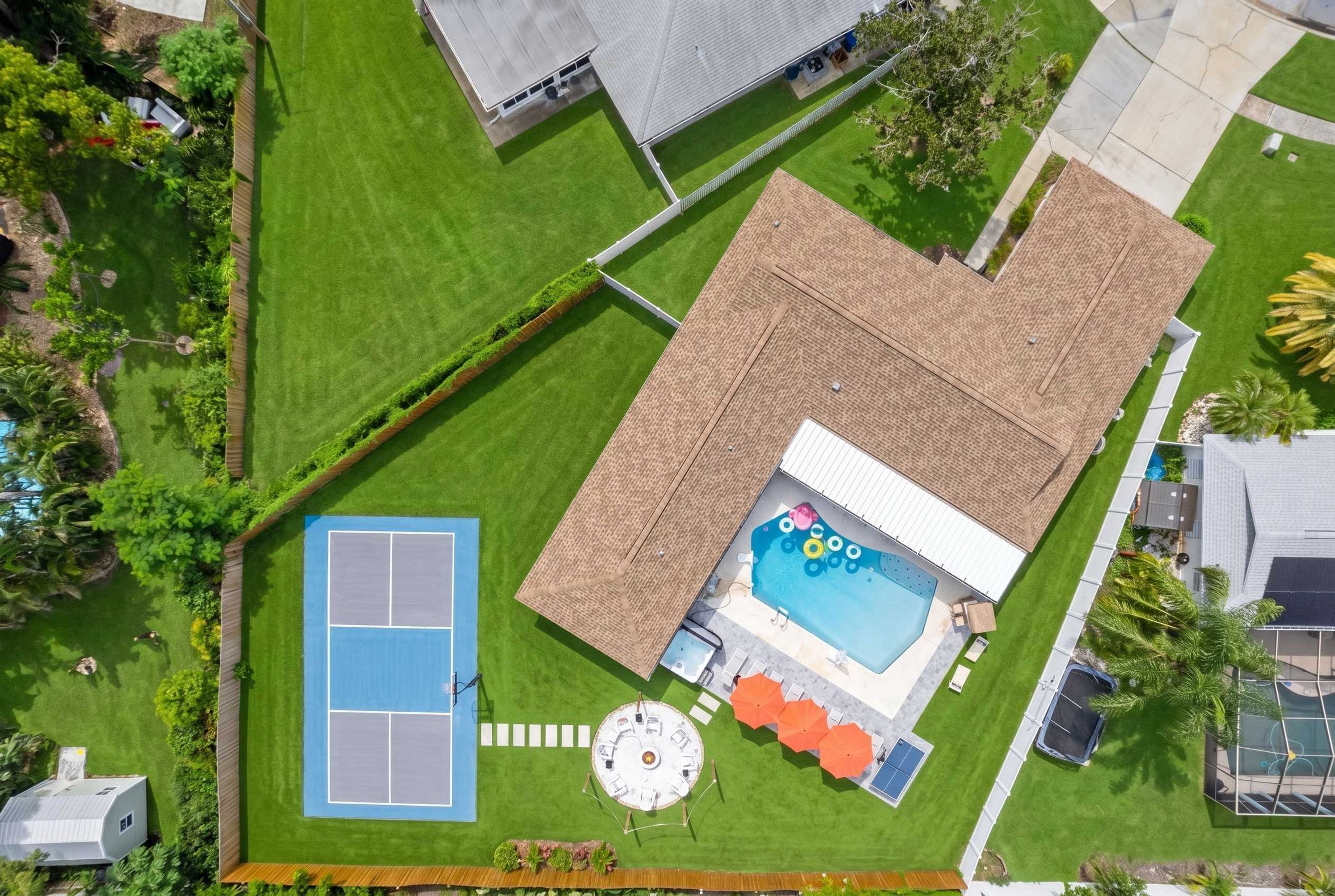Una propiedad residencial con piscina, cancha de tenis y terraza cubierta.