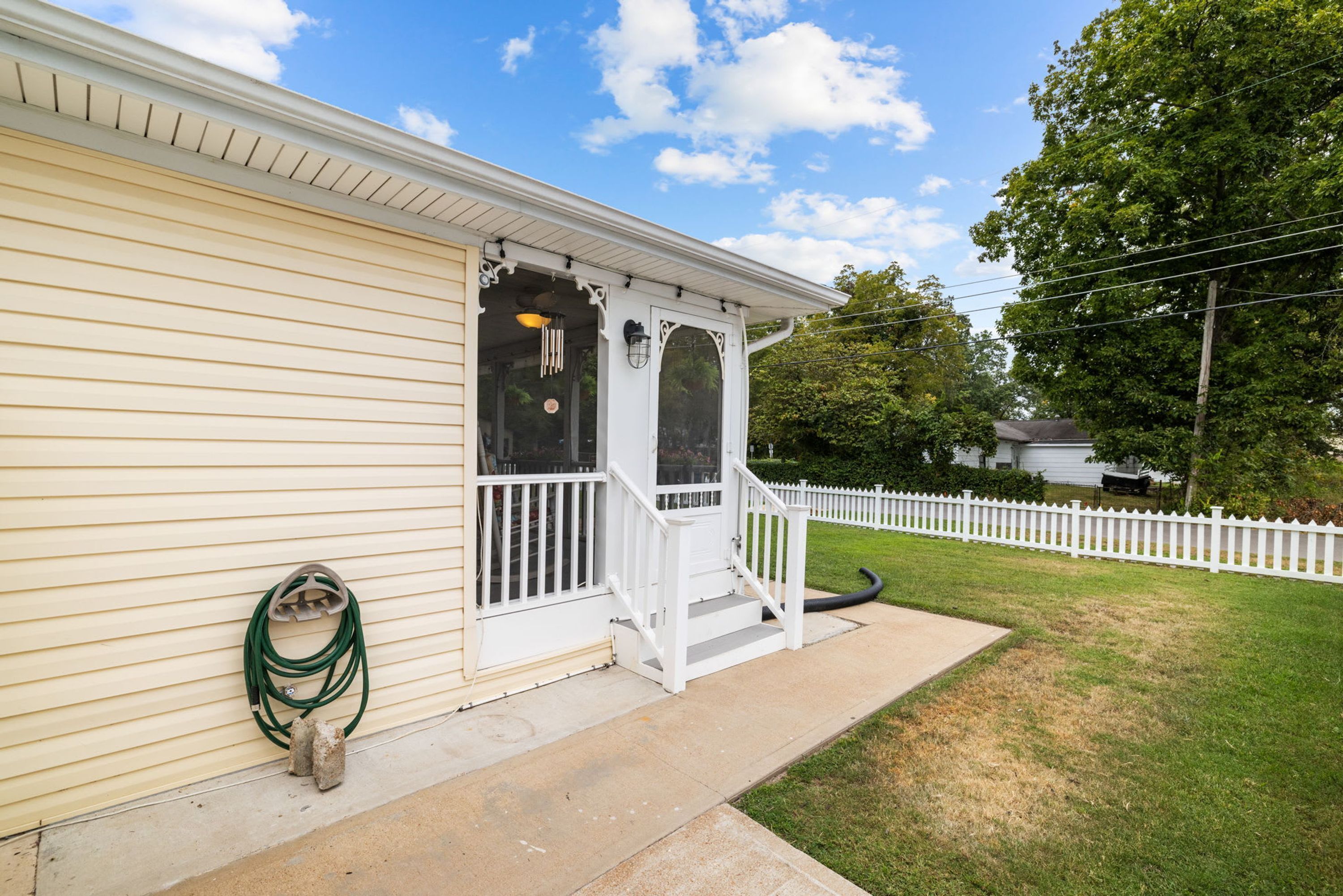A house with a porch, a white fence, and a garden.