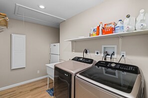 A laundry room with two washers and dryers, a white refrigerator, and a shelf with cleaning supplies. - Kimmswick Porch Haven Hot Tub Yard (Imperial)
