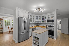 A modern kitchen with white cabinetry, stainless steel appliances, and a wooden island. - Kimmswick Porch Haven Hot Tub Yard (Imperial)