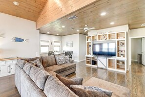 A living room with a sectional sofa, a television, and a wooden ceiling. - Nauti Paradise- Private Pool Game Room (Port Aransas)