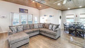 Ein modernes Wohnzimmer mit Ecksofa, Essbereich und Deckenventilator.