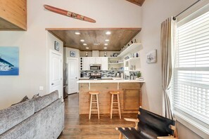 A compact kitchen with a central island, wooden flooring, and a ceiling with exposed beams. - Nauti Paradise- Private Pool Game Room (Port Aransas)
