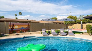 A swimming pool with lounge chairs and umbrellas, a mural on the wall, and a basketball hoop. - Sport Court Private Heated Pool Mini Golf More (Glendale)