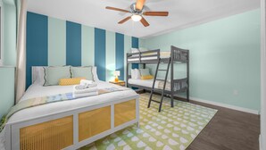 Ein Zimmer mit Etagenbett, Einzelbett, Deckenventilator und einem gemusterten Teppich.