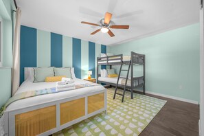 A room with a bunk bed, a single bed, a ceiling fan, and a patterned rug. - Pool Games More Fun for Everyone (Palm Harbor)