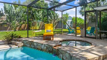 Um quintal com piscina, banheira de hidromassagem e um espaço coberto com área de estar.