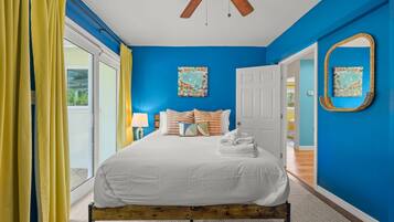 A bedroom with a bed, a ceiling fan, a door, and a window.
