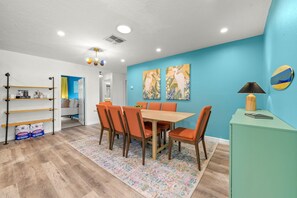 A dining area with a table and chairs, a coffee bar, and a wall with two paintings. - Pool Games More Fun for Everyone (Palm Harbor)