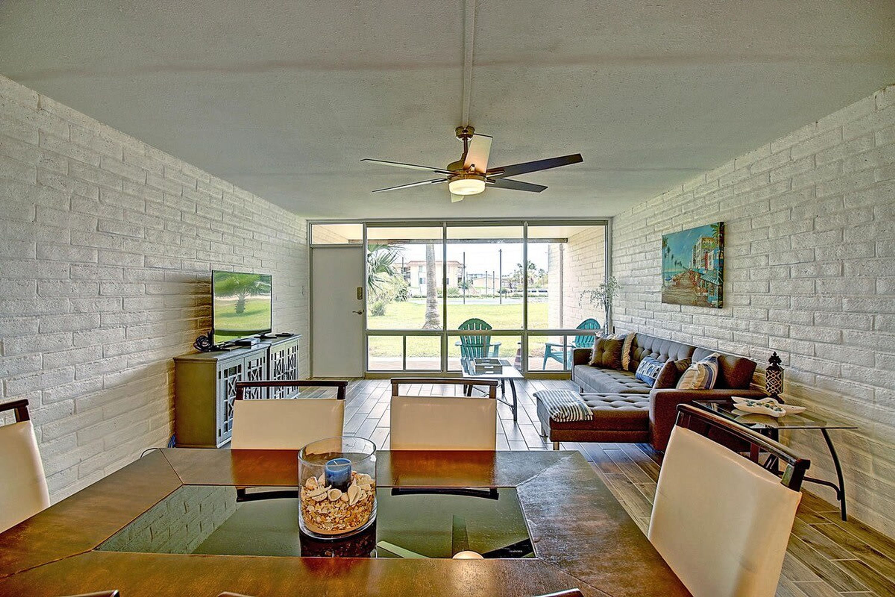 A living room with a television, a ceiling fan, a sofa, and a coffee table.