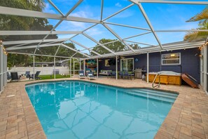A swimming pool with a covered area, lounge chairs, and a hot tub. - Epic Indoor Slide Pool Hot Tub Mini Golf Fire Pit (Madeira Beach)