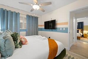 A hotel room with a bed, a ceiling fan, a flat-screen TV, and a view of another room. - Epic Indoor Slide Pool Hot Tub Mini Golf Fire Pit (Madeira Beach)