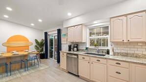 Una cocina moderna con armarios de colores claros, encimera de granito y lavavajillas.