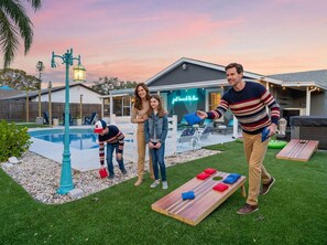 A backyard with a pool, a wooden deck, and a neon sign. - Pool Hot Tub Game Room More - Sleeps 10 (Bradenton)