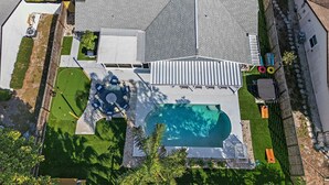 Ein Wohnhaus mit Swimmingpool, Terrassensitzgelegenheiten und einem umzäunten Garten.
