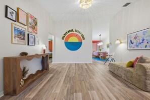 A modern interior with a reception desk, framed artwork, a wall mural, and a dining area. - Sleeps 14 Heated Pool Spa Arcade Putt Putt (Largo)