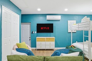 A room with a bunk bed, a TV mounted on the wall, a white dresser, and a door. - Sleeps 14 Heated Pool Spa Arcade Putt Putt (Largo)