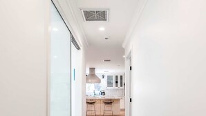 Un pasillo con un tapete estampado que conduce a una cocina con suelo de madera y armarios blancos.
