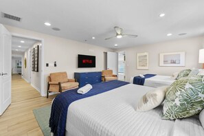 Une chambre d’hôtel avec un lit, un téléviseur affichant le logo « NETFLIX », un ventilateur de plafond et une porte donnant sur une autre pièce.