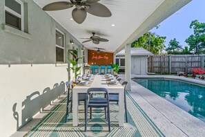 Ein Essbereich im Freien mit Pool, Deckenventilatoren und einer Neonreklame.