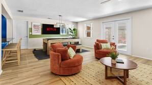 A modern living room with a flat-screen TV, two armchairs, a coffee table, and a ceiling fan. - Sleeps 20 Basketball Court Pool Movie Room (Bradenton)